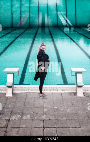 Giovane donna vestiti di nero con il cane di armi dal rustico piscina concetto da sogno Foto Stock