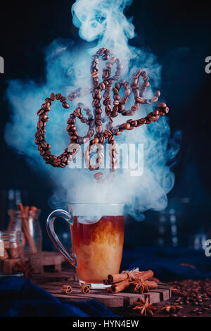 Caffè fumante con lettere fatte di fagioli su sfondo scuro Foto Stock
