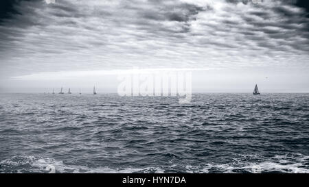 Yacht a vela barca regata gara sul mare irlandese di acqua su un giorno nuvoloso. fotografia in bianco e nero. Foto Stock