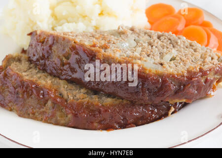 Classic American polpettone fatto con carne di manzo macinata farina di avena cipolle e un ketchup zucchero marrone smalto mostarda servita con purè di patate e carote monete Foto Stock