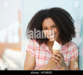 Close up ritratto di un sorridente giovane donna tenendo cono gelato all'aperto in estate Foto Stock