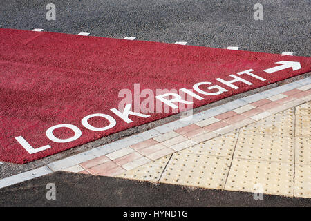 Dipinto di guardare a destra cartello stradale e la freccia su una superficie strutturata attraversamento pedonale in Buckingham Foto Stock