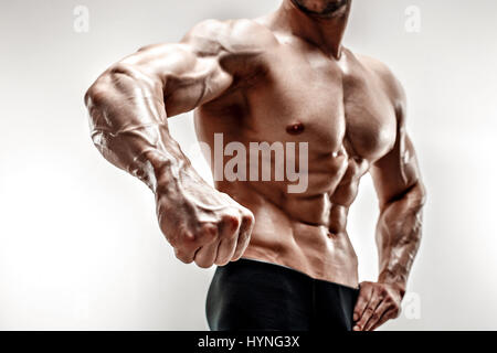 Bello muscoloso bodybuilder dimostra il pugno e la vena, vasi sanguigni. Studio shot su sfondo bianco. Man mano Foto Stock