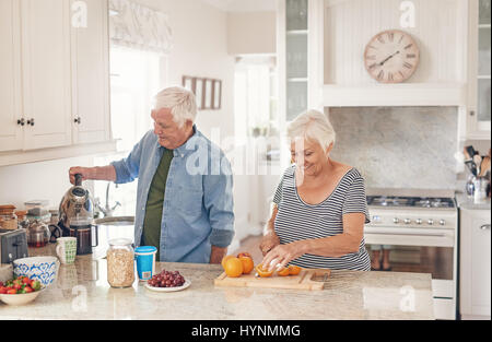 Felice coppia senior preaparing una sana prima colazione nella loro cucina Foto Stock