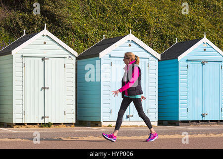 Bournemouth Dorset, Regno Unito. 6 apr, 2017. Regno Unito: meteo bella calda giornata di sole come testa di visitatori al mare per rendere la maggior parte del sole a Bournemouth spiagge. Donna che cammina lungo la passeggiata sulla spiaggia del passato di capanne. Credito: Carolyn Jenkins/Alamy Live News Foto Stock
