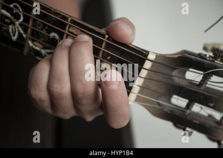 La mano dell'uomo close up contiene una corda su una chitarra Firma Timbro Foto Stock