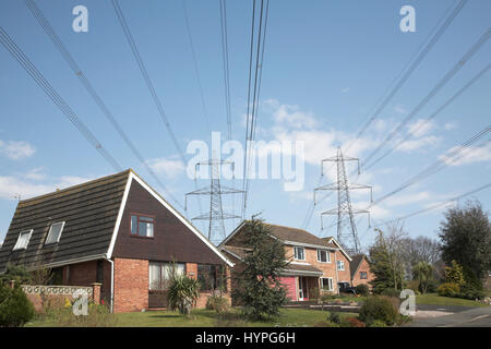 Linee elettriche ad alta tensione dalla centrale nucleare di Sizewell sulle case suburbane, Aldingham, Suffolk, Inghilterra, Regno Unito Foto Stock