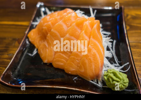 Sashimi di salmone su un nero piastra ceramica con la porzione di Wasabi Foto Stock