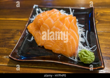 Sashimi di salmone su un nero piastra ceramica con la porzione di Wasabi Foto Stock