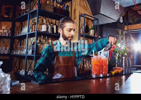 La barista ride facendo un cocktail presso il bar Foto Stock