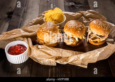 In casa Mini Hamburger di manzo con insalata Coleslaw sul piccolo tagliere di legno. Carne alla Brace panini sul tavolo rustico. Foto Stock