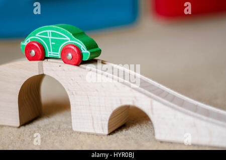 Un giocattolo auto in legno sulla parte superiore di un giocattolo di ponte di legno. La macchina corre lungo una via con scanalature di guida si tratta di ruote. Foto Stock