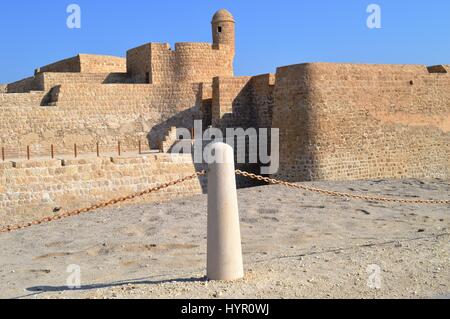 Un bollard allineato alla torre di avvistamento del Bahrain Fort at Al Qalah, Bahrein, in Medio Oriente. Foto Stock