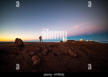 Gli escursionisti a piedi il sentiero sulla cima del cratere Haleakala a Maui con l'altitudine elevata osservatorio in background, Terra ombra visibile nel cielo. Foto Stock