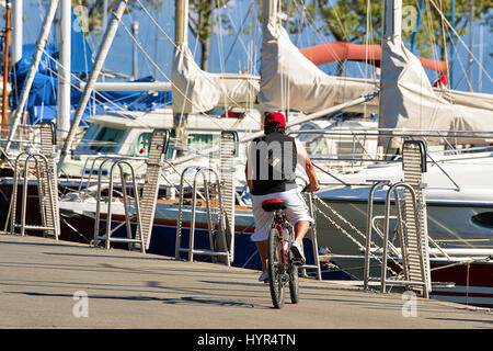 Uomo in sella ad una bicicletta al terrapieno di Marina sul Lago di Ginevra in Lausanne Ouchy villaggio di pescatori, Svizzera Foto Stock