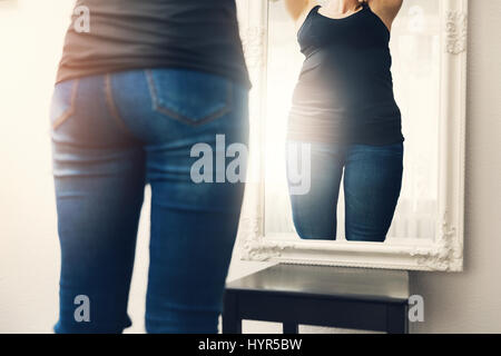 Anoressia concetto - donna guarda la sua riflessione di grasso in specchio Foto Stock