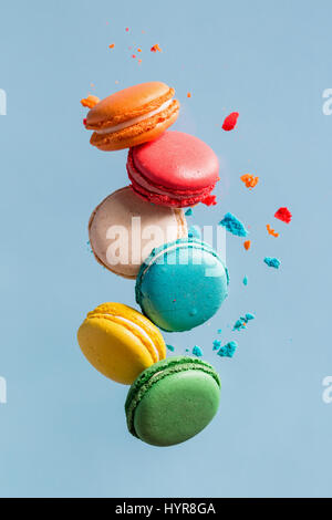 Diversi tipi di amaretti in movimento la caduta sul fondo azzurro. Dolce e colorata amaretti francese di caduta o battenti in movimento. Foto Stock