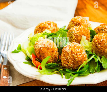 Falafel.le sfere di ceci con sesamo e insalata verde sulla piastra Foto Stock