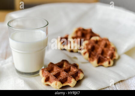 In casa belga di cialde di Liegi con un bicchiere di latte sul tavolo Foto Stock