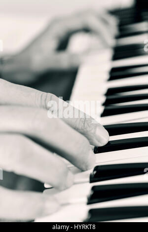 Primo piano di un giovane uomo caucasico suonare una tastiera elettronica, in bianco e nero Foto Stock