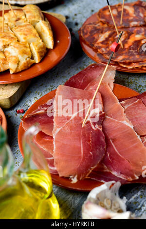 Primo piano di alcune piastre con un assortimento di spagnolo diversi salumi, come il prosciutto Serrano e il chorizo, a dadini di frittata spagnola e una ampolla con Foto Stock