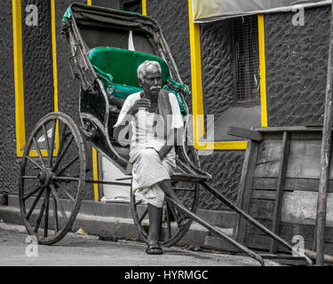 Una mano rickshaw estrattore prendendo un tè becco ed essendo considerato Foto Stock