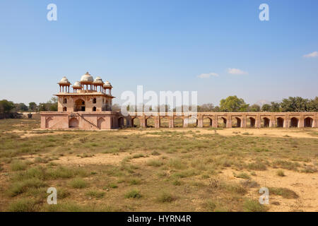 Il sito storico di Jal Mahal in Rajasthan in India con il colore rosa muratura a secco sarovar con vegetazione a macchia e alberi sotto un cielo blu Foto Stock