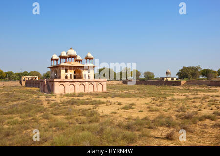 Colore rosa di edifici del sito storico di Jal Mahal in Rajasthan con sarovar secco e alberi sotto un cielo blu chiaro in India Foto Stock