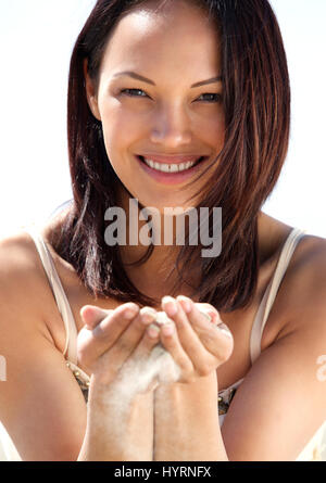 Close up ritratto di una bella donna sorridente con sabbia cadere attraverso le dita Foto Stock