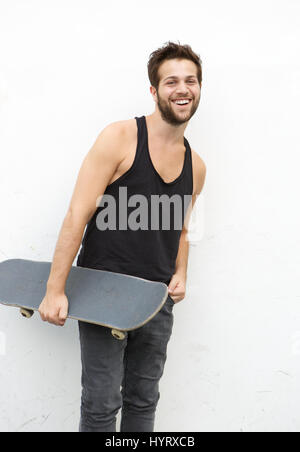 Ritratto di un sorridente giovane azienda skateboard su sfondo bianco Foto Stock