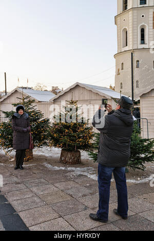 Vilnius, Lituania - 4 Dicembre 2016: persone fotografie di alberi di Natale con il mercato principale di albero di Natale con velatura decorativa ghirlande sul retro Foto Stock