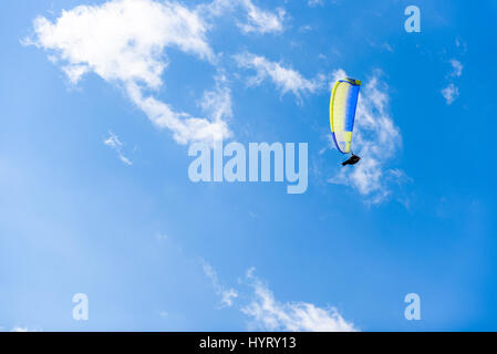 Parapendio volare contro il cielo blu con nuvole bianche. Paracadute su un blu chiaro giornata di sole. Foto Stock