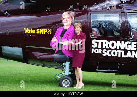 SNP leader e primo ministro Nicola Storione pone accanto a un gigante immagine di se stessa il blasonato su un appositamente commissionati campagna elettorale elicottero Foto Stock