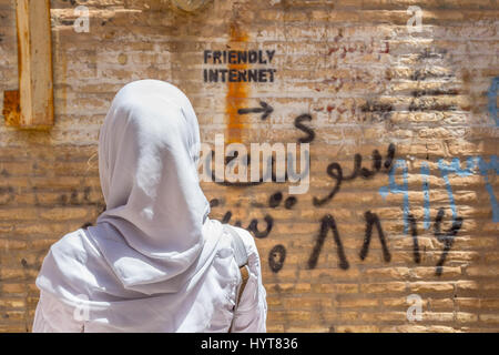 YAZD, IRAN - Agosto 18, 2016: donna velata guardando una scritta sul muro che indica uncensored spot Internet foto di una donna che indossa un sca Foto Stock