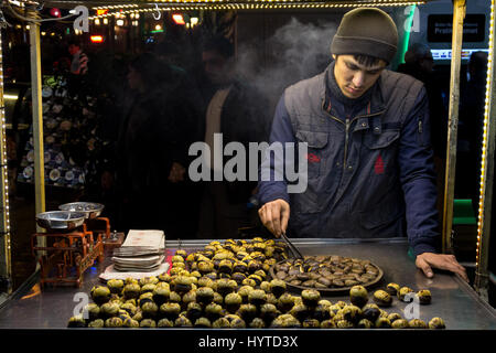 ISTANBUL, Turchia - 28 dicembre 2015: la foto di un giovane venditore di castagno in una fredda sera d'inverno sulla strada Istiklal giovane venditore di castagne su Istikl Foto Stock