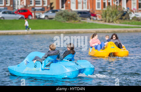 Giornata di divertimenti. I bambini in pedalo barche su una giornata di primavera su un lago in barca all'Oyster Pond in Littlehampton, West Sussex, in Inghilterra, Regno Unito. Foto Stock