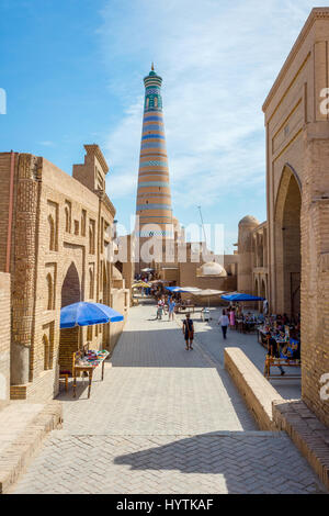 KHIVA, UZBEKISTAN - 7 settembre: persone che camminano nella strada stretta a Khiva città vecchia e minareto di dietro. Settembre 2016 Foto Stock