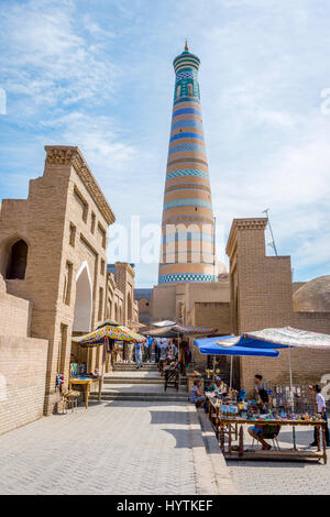 KHIVA, UZBEKISTAN - 7 settembre: persone che camminano nella strada stretta a Khiva città vecchia e minareto di dietro. Settembre 2016 Foto Stock