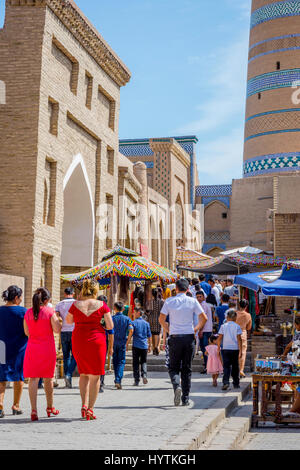 KHIVA, UZBEKISTAN - 7 settembre: persone che camminano nella strada stretta a Khiva città vecchia e minareto di dietro. Settembre 2016 Foto Stock