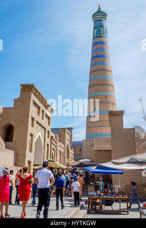 KHIVA, UZBEKISTAN - 7 settembre: persone che camminano nella strada stretta a Khiva città vecchia e minareto di dietro. Settembre 2016 Foto Stock