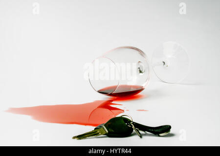 Carkeys giacente sulla superficie. Caduto wineglass con fuoriuscite di vino rosso e il sughero in background.concetto non per guida in stato di ebbrezza Foto Stock