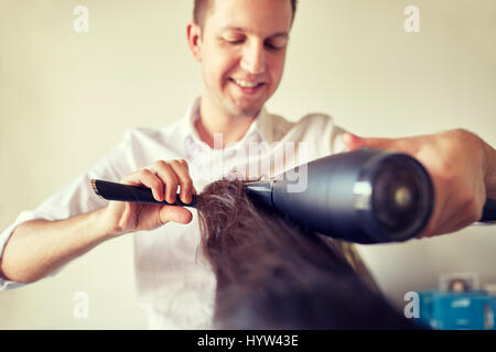 Close up stylist rendendo pettinatura a salon Foto Stock