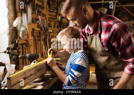 Padre e Figlio con il righello di legno di misura in officina Foto Stock