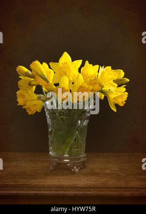 Mazzetto di primavera narcisi in un antico vaso di vetro seduto sul tavolo rustico Foto Stock