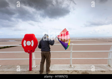 Persona alle prese con ombrello collassato in una giornata di vento al coatal cittadina e la passeggiata lungomare di Rhyl nel Galles del Nord Foto Stock