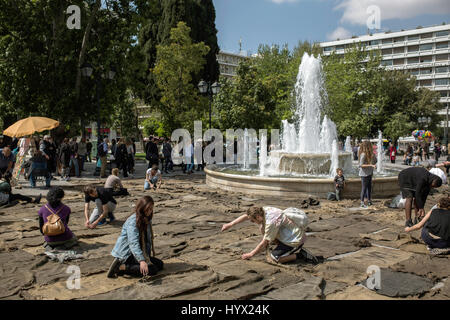 Auf dem Syntagma-Platz di Atene (Griechenland) nähen am 07.04.2017 im Rahmen der documenta 14 bei der prestazioni 'Check Point - Prosfygika' des Künstlers Ibrahim Mahama aus Ghana junge Menschen mit grobem Faden und dicker Nadel Jute-Säcke zusammen. Die internationale Kunstausstellung documenta 14 wird erstmals vom 08. Aprile bis 16. Juli 2017 zunächst in Athen und vom 10. Juni bis zum 17. Settembre 2017 a Kassel zu sehen sein. (Zu dpa 'Umzug nach Athen "rettet die Idee der documenta" vom 07.04.2017) Foto: Angelos Tzortzinis/dpa Foto Stock