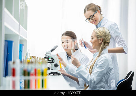 Giovane donna sorridente scienziati azienda tubi di test con reagenti in laboratorio Foto Stock