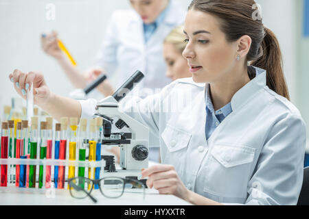 Giovani donne scienziato che lavora con microscopio in laboratorio chimico Foto Stock