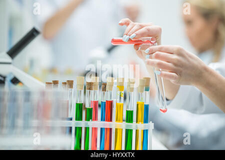 Close-up vista parziale della donna scienziato tenendo le provette per la prova in laboratorio chimico Foto Stock