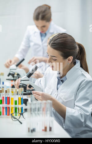 Giovani donne scienziato che lavora con microscopio in laboratorio chimico Foto Stock